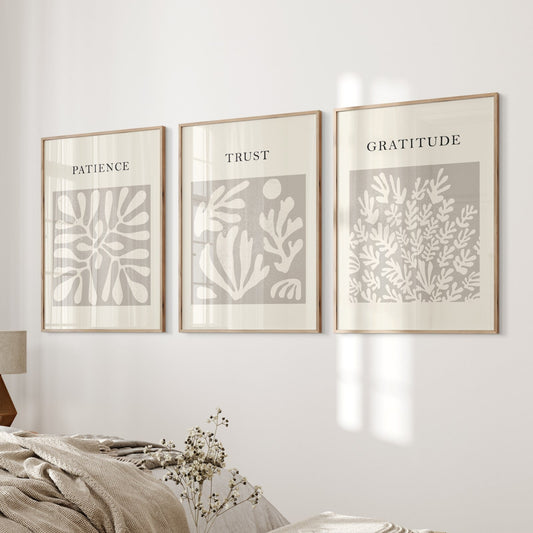 Three framed prints on a wall with motivational phrases above a bed in a bedroom.