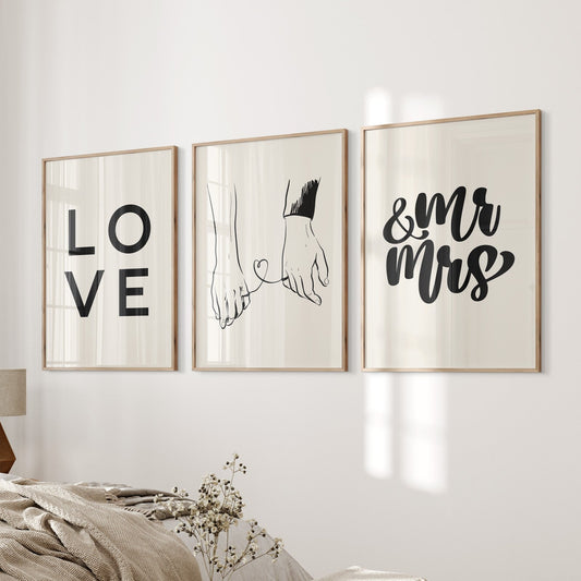 Three framed prints on a wall with 'LOVE', 'Hand in Hand', and '& MR MRS' text in a living room setting.