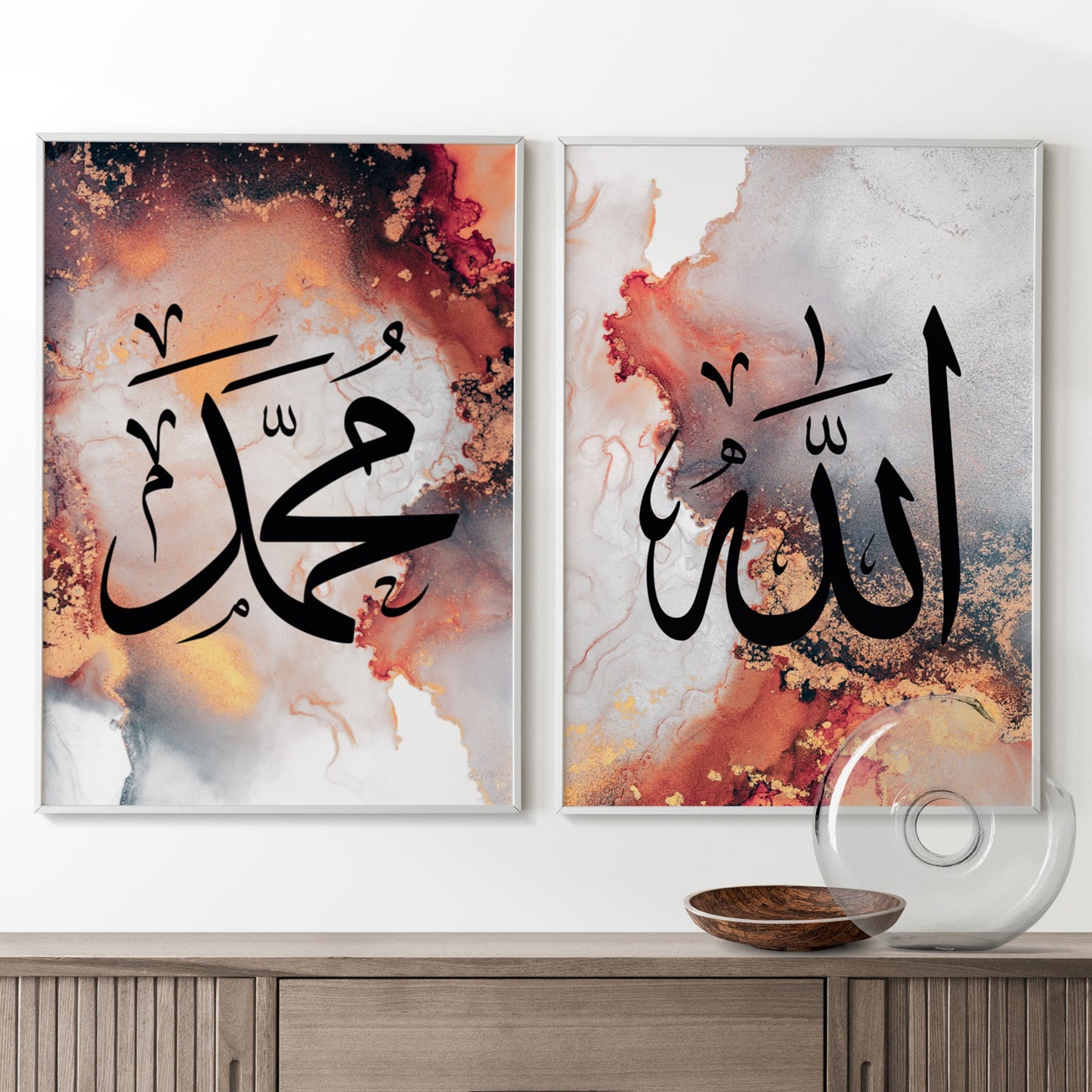 Two abstract art pieces with Arabic calligraphy on a white wall above a wooden cabinet.