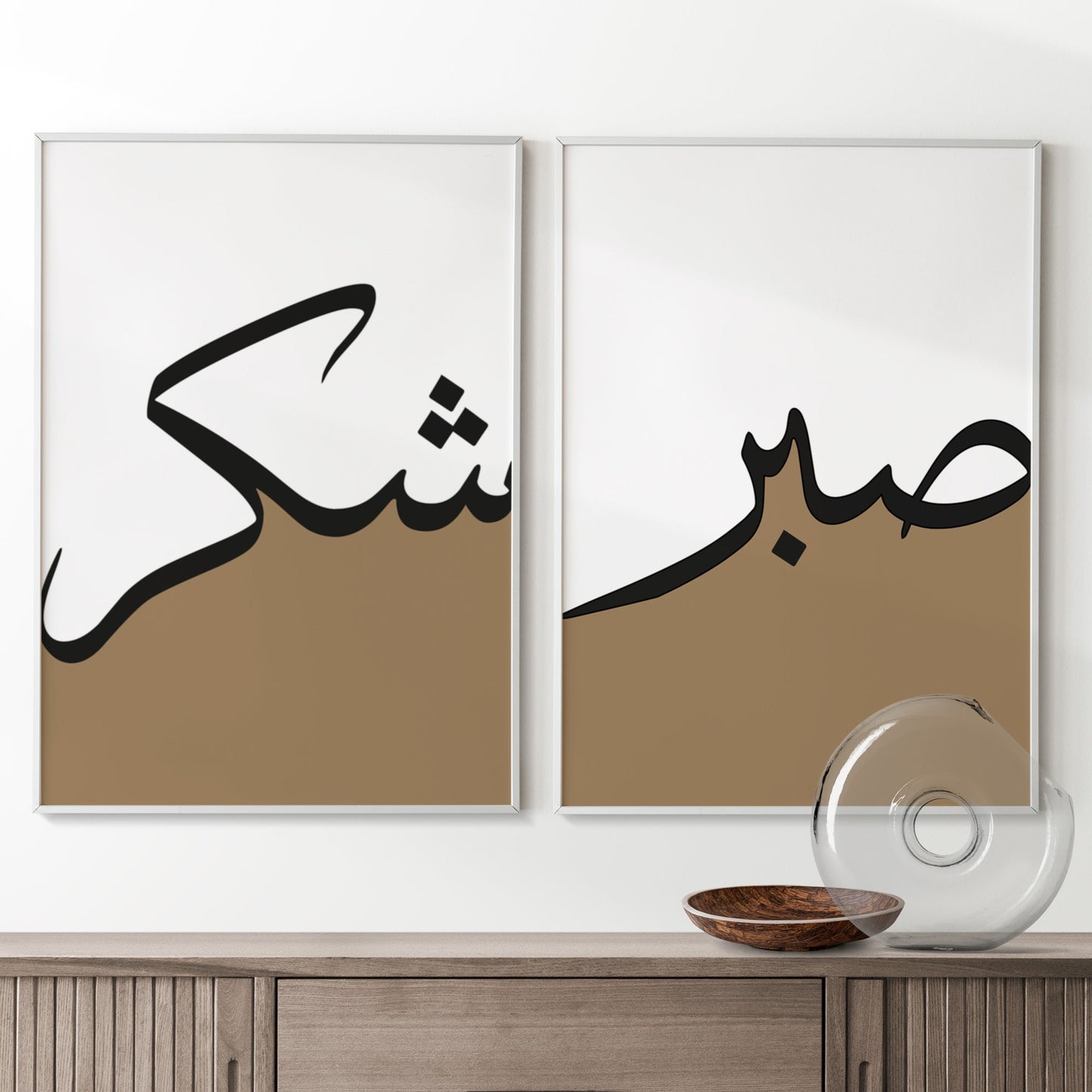 Two framed pieces of art with Arabic calligraphy on a white wall above a wooden cabinet.