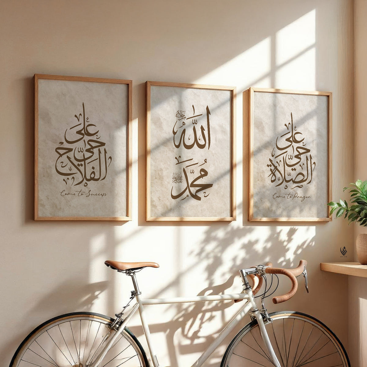 Three framed pieces of art with Arabic calligraphy on a wall with a bicycle in the foreground.
