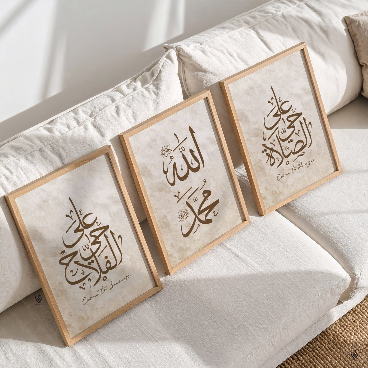 Three framed pieces of art with Arabic calligraphy on a white sofa in the living room.