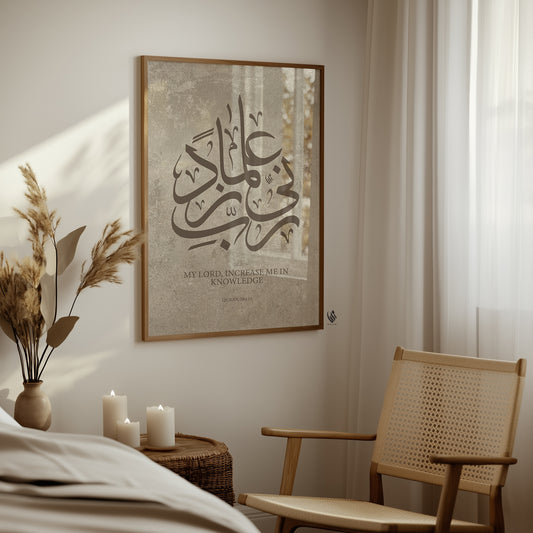 Calm neutral corner with wooden chair, candles, and soft decor, displaying a framed Arabic calligraphy artwork “Rabbi Zidni Ilma” with the meaning “My Lord, increase me in knowledge” on a warm beige stone-style background.