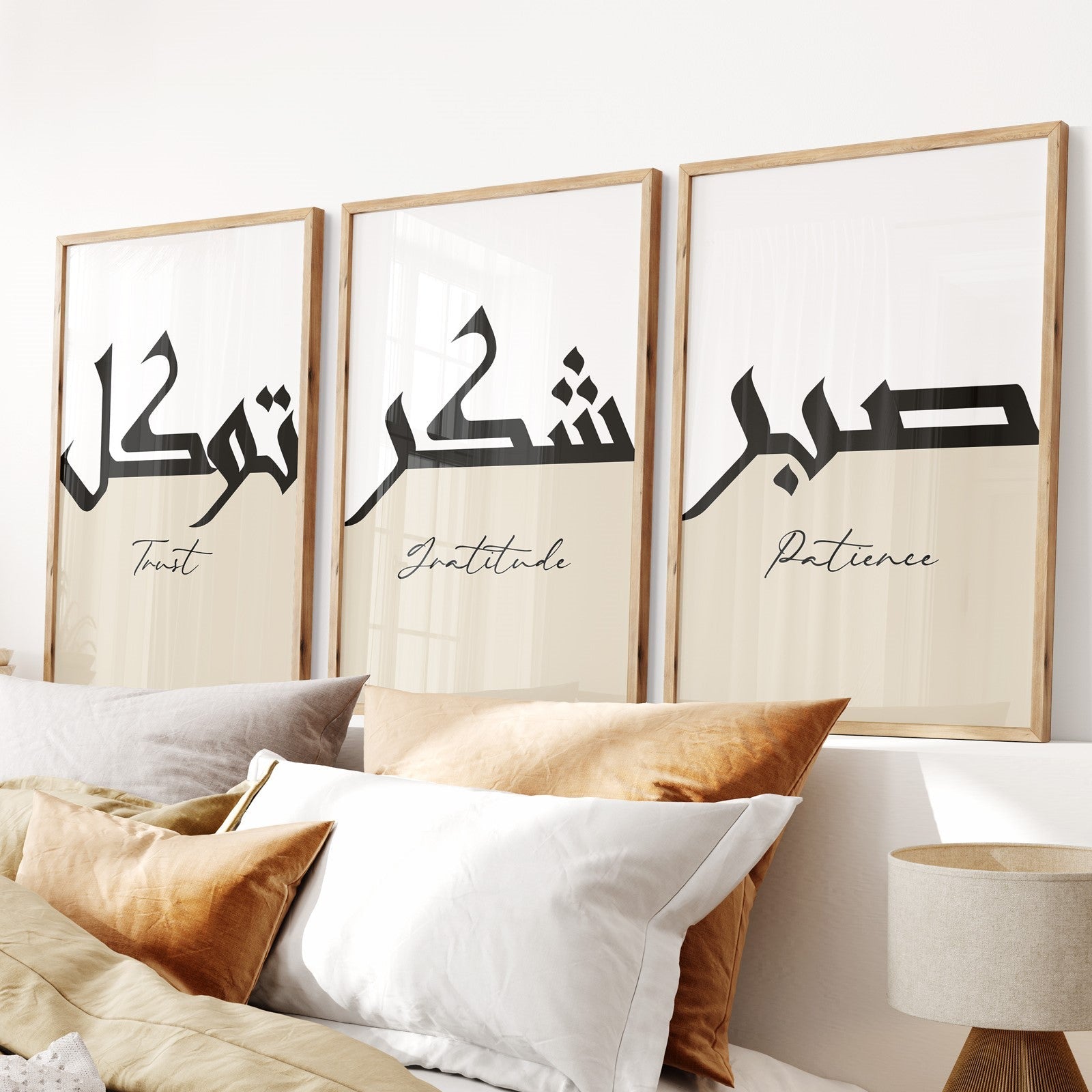 Three framed pieces of art with Arabic calligraphy and English words on a wall above a bed.