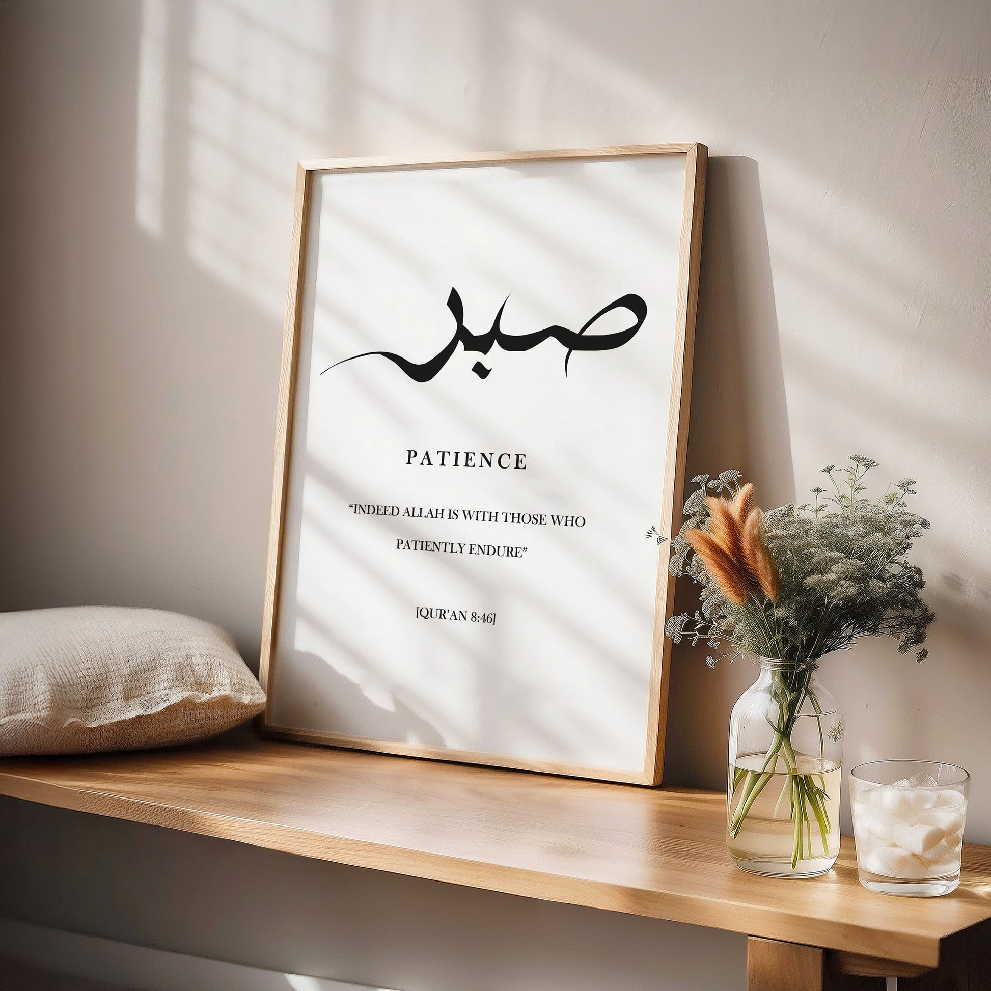 Sabr Patience quran ayah on a framed poster with Arabic text and English translation on a wooden shelf with decorative items.