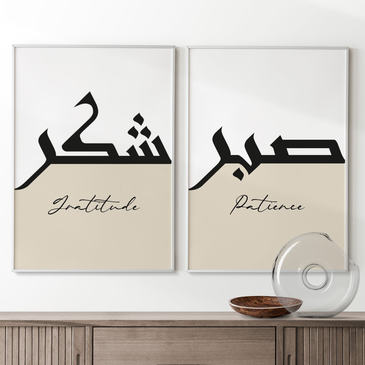 Two framed prints with Arabic calligraphy and English words on a wall above a wooden cabinet.