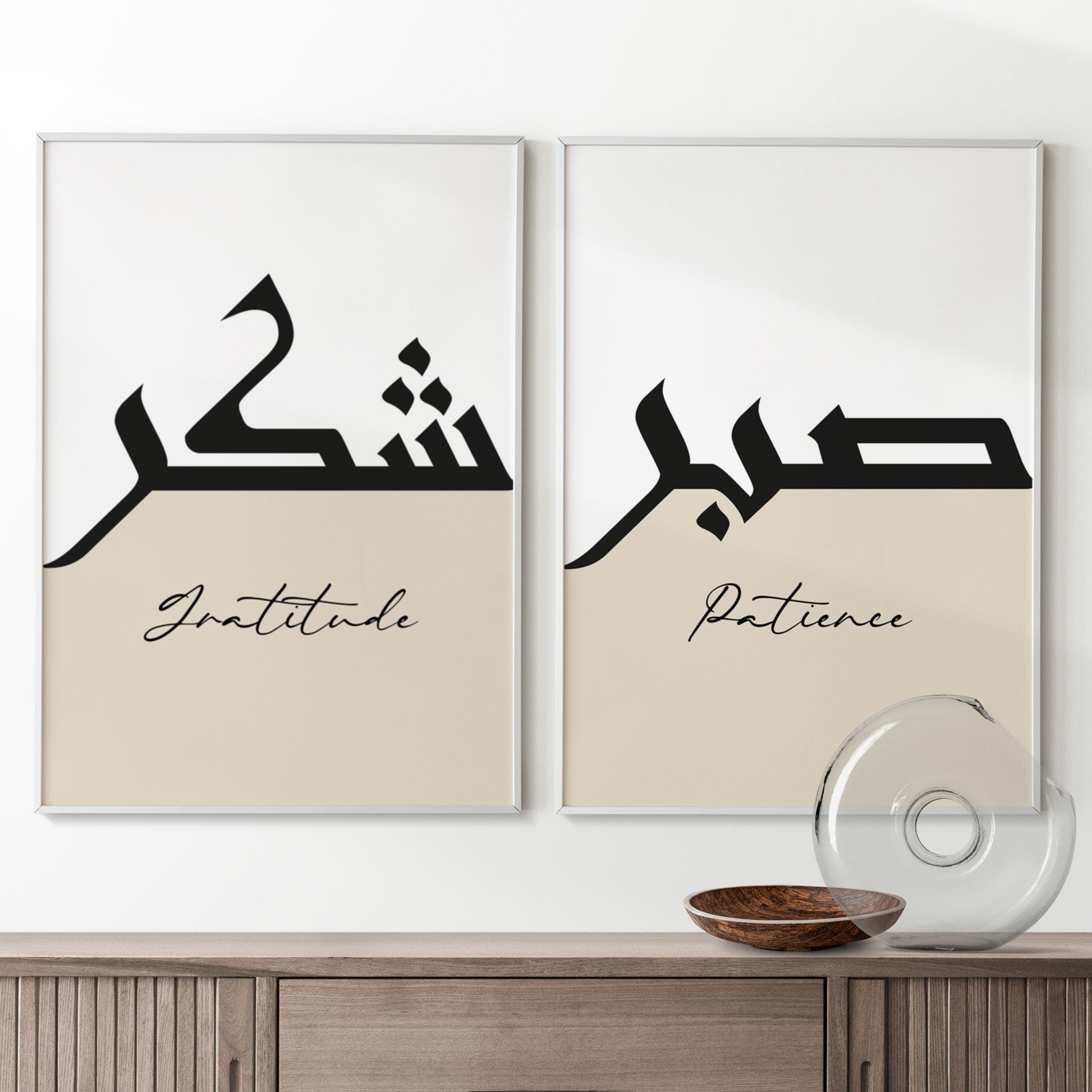 Two framed prints with Arabic calligraphy and English words on a wall above a wooden cabinet.