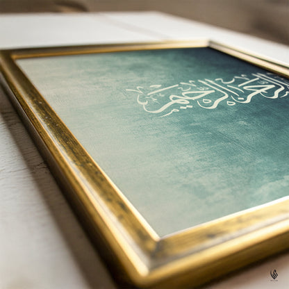 Close-up of Bismillah Arabic calligraphy in a gold frame, with white script over a distressed teal and sage green textured Islamic art background.