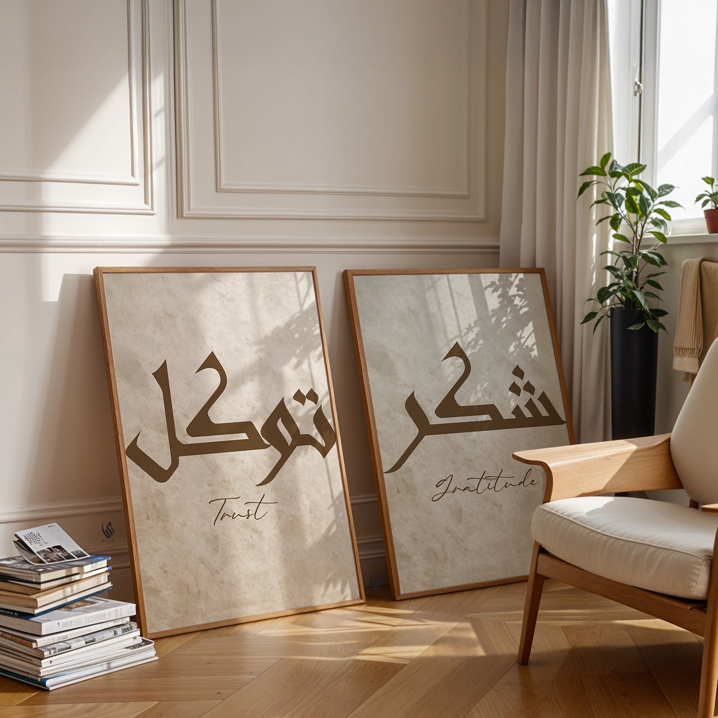 Two framed Arabic calligraphy artworks on a wall with a chair and books in the foreground.