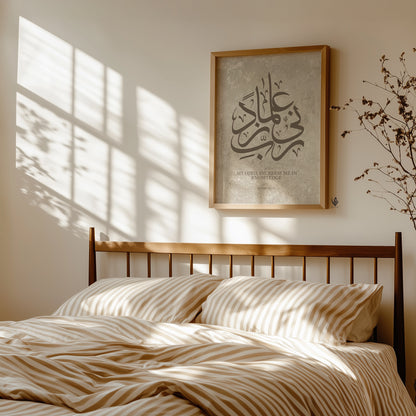 Minimalist bedroom interior with beige striped bedding and warm sunlight casting window shadows, featuring a framed Islamic wall art print with Arabic calligraphy “Rabbi Zidni Ilma” on a soft stone-textured background in neutral tones.