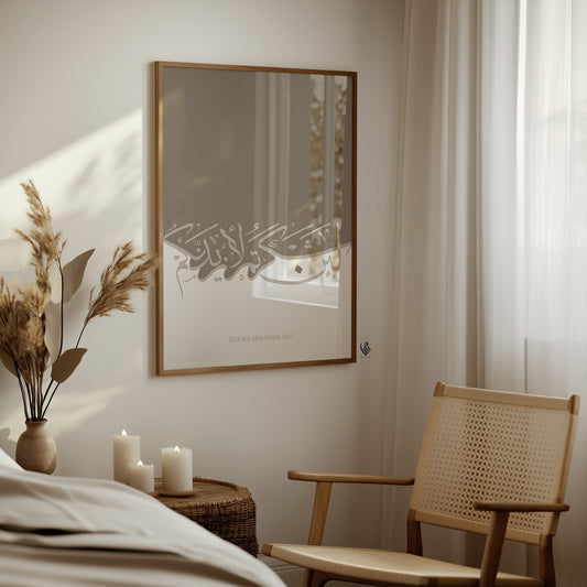 Surah Ibrahim 14:7 Arabic calligraphy wall art in a wood frame beside a woven chair and soft neutral decor.