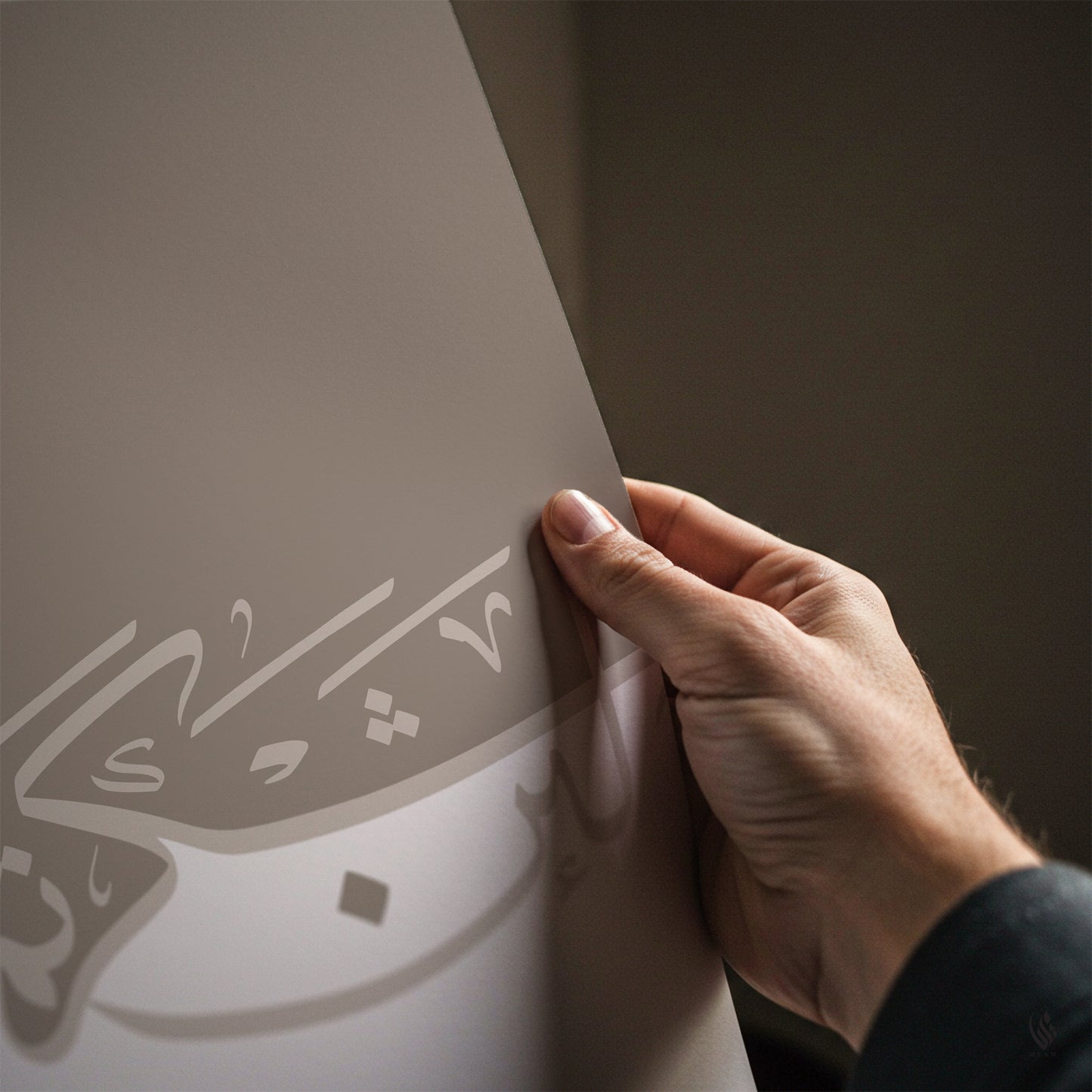 Hand holding a piece of paper with Arabic text against a dark background