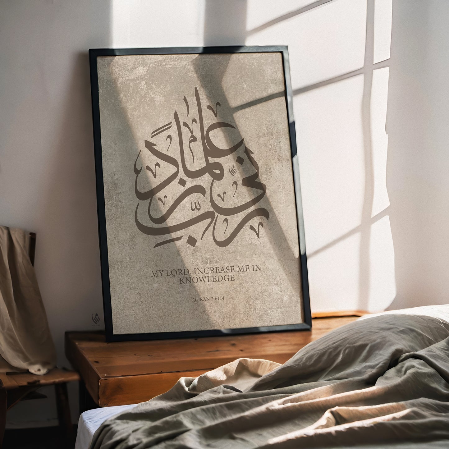 Framed Islamic wall art featuring Arabic calligraphy on a soft beige textured background, styled in a modern neutral interior.