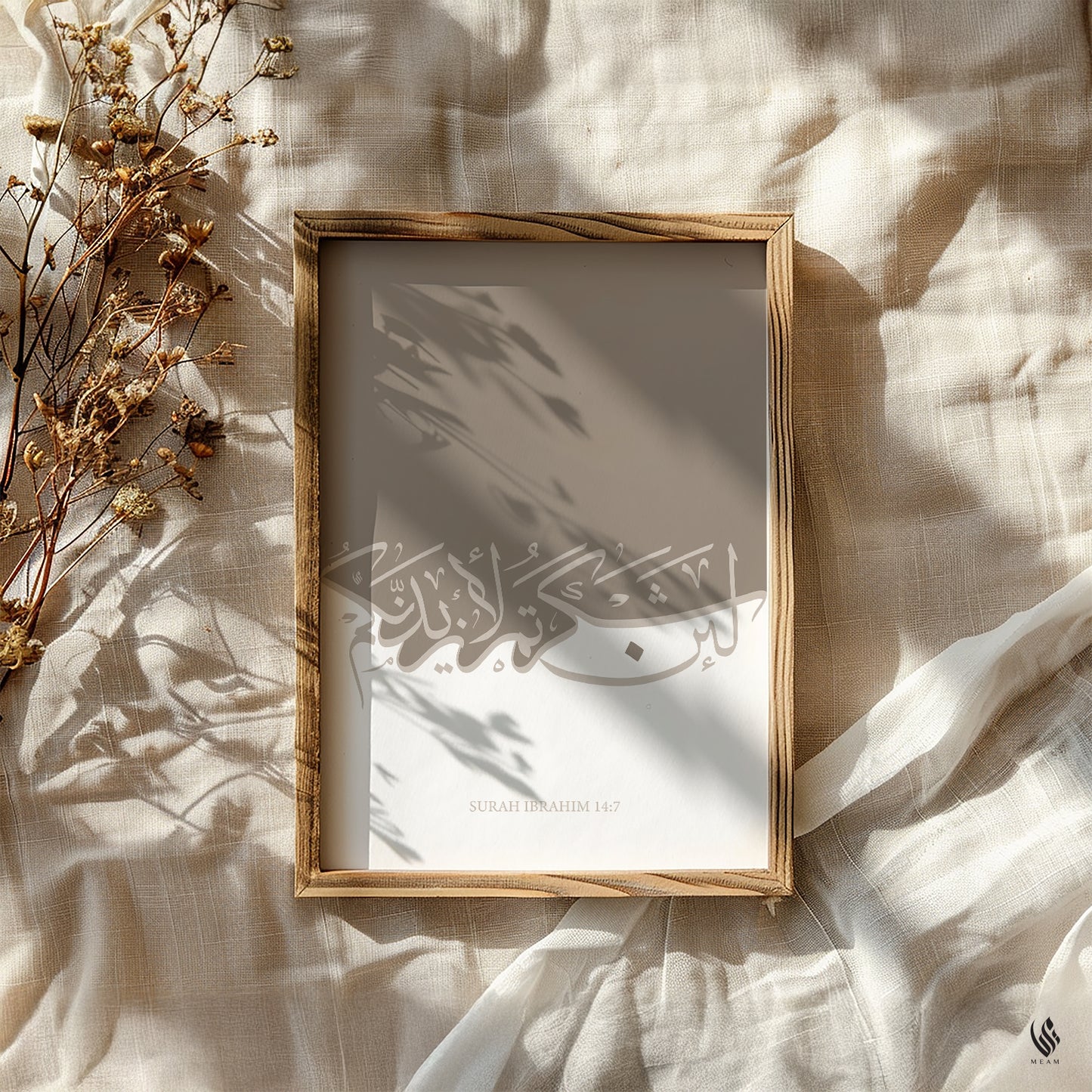 Framed artwork with Arabic calligraphy on a textured surface with dried flowers. Minimalist Quran wall art, Surah Ibrahim 14:7, beige and white palette, framed art print