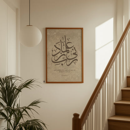 Framed Arabic calligraphy artwork on a wall in a home setting with a staircase and plant.
