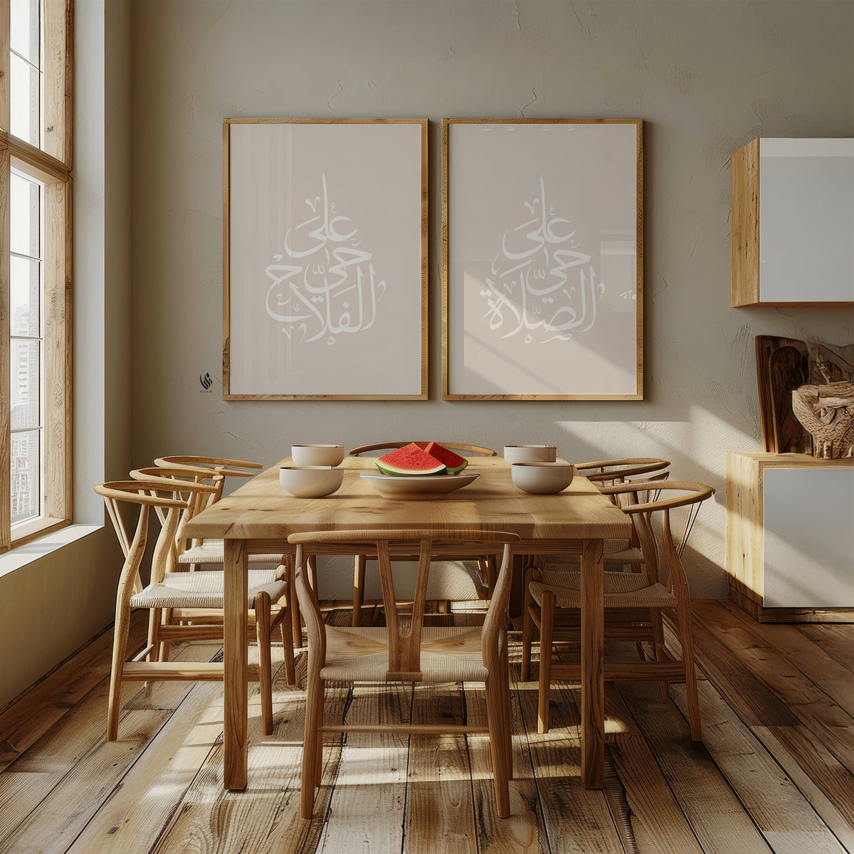 Set of 2 neutral Islamic wall art prints above a wooden dining table, featuring white Adhan Arabic calligraphy in elegant pearl drop-shaped compositions.