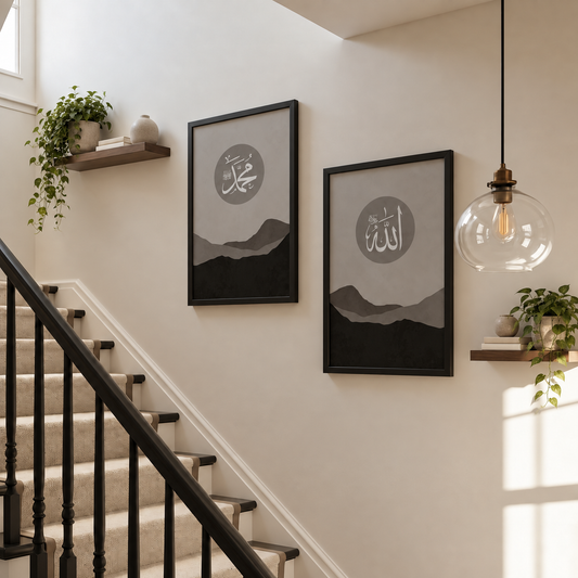 Allah and Muhammad Islamic wall art set of 2 in black frames, featuring white Arabic calligraphy above layered grey, taupe and black mountain landscapes.