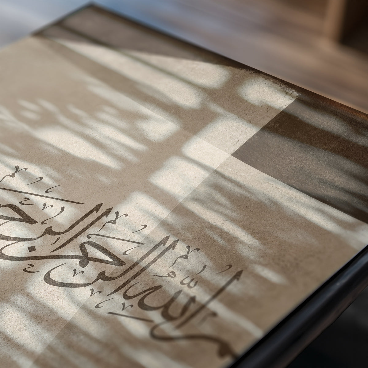 Close-up of the second Bismillah print showing Arabic calligraphy, cream and brown geometric forms, textured surface and soft window shadows.