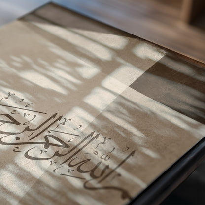 Close-up of the second Bismillah print showing Arabic calligraphy, cream and brown geometric forms, textured surface and soft window shadows.