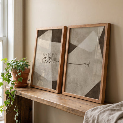 Neutral Bismillah Arabic calligraphy wall art set of 2 displayed in wood frames on a rustic console, with beige, taupe and brown abstract shapes.