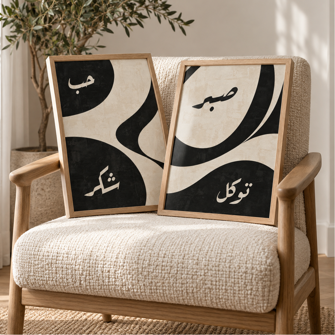 Set of two black and beige Islamic wall art prints with Arabic calligraphy, displayed in wooden frames on a cream boucle chair beside a tall olive tree in a warm neutral interior with soft natural light and modern decor.