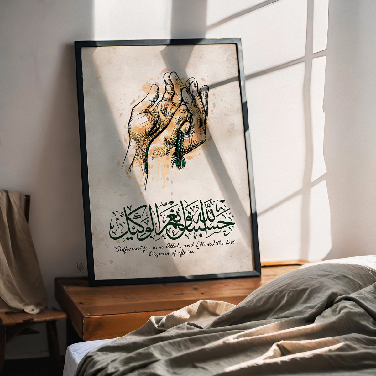 Hasbunallahu Wa Ni'mal Wakeel Islamic wall art in a black frame beside a bed, with praying hands, green tasbih beads and Arabic calligraphy in warm sunlight.