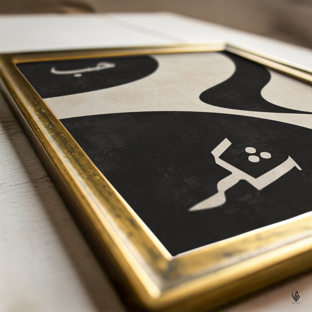 Close-up of Hubb and Shukr Islamic wall art in a gold frame, with cream Arabic calligraphy over bold black and warm beige abstract textured curves.