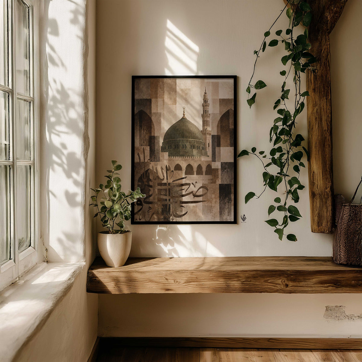 Madina mosque wall art in a black frame above a rustic wooden bench, surrounded by green plants and window light.