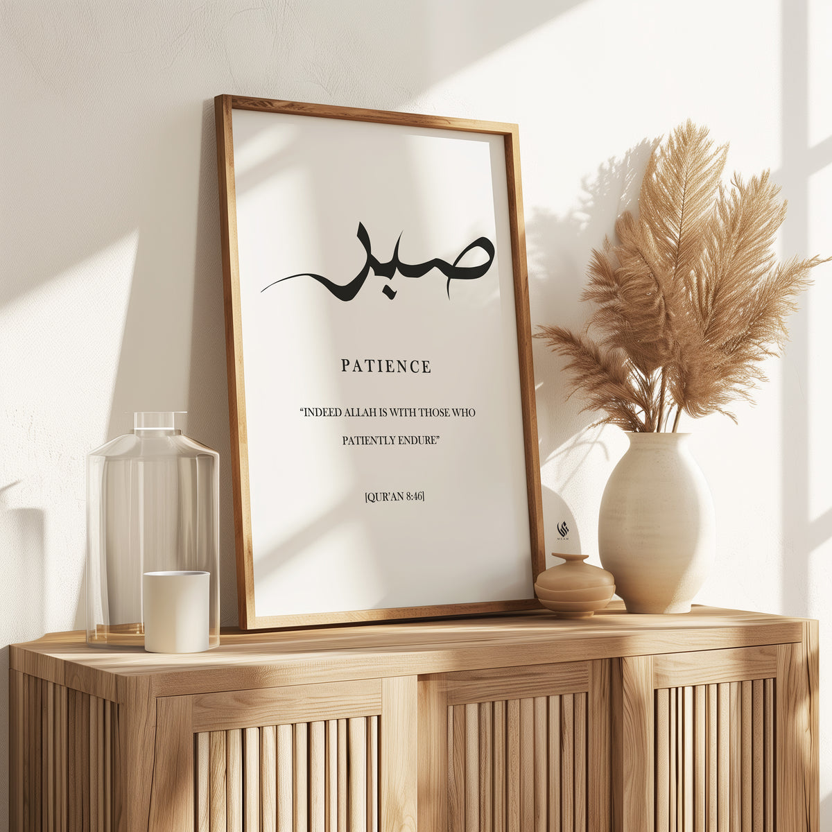 Sabr patience Islamic wall art in a light wood frame, featuring black Arabic calligraphy and Quran 8:46 styled on a warm neutral wooden console.