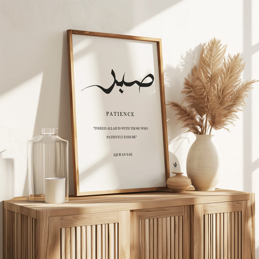 Sabr patience Islamic wall art in a light wood frame, featuring black Arabic calligraphy and Quran 8:46 styled on a warm neutral wooden console.
